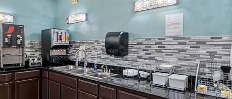 Una cocina con cafetera, secamanos y dispensador de toallas de papel.