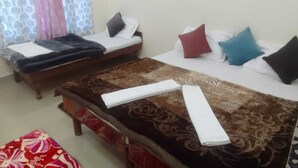 A hotel room with two single beds, each with a different patterned bedspread and pillows.