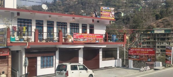A building with multiple signs advertising local businesses, including a tea stall and a restaurant. - Hotel Kalyan Palace And Restaurant (Pipalkoti)