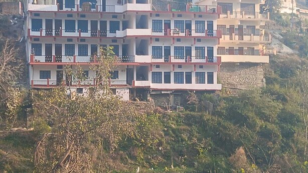 A multi-story building with balconies, situated on a hillside.