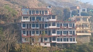 A multi-story building with balconies, located in a hilly area.