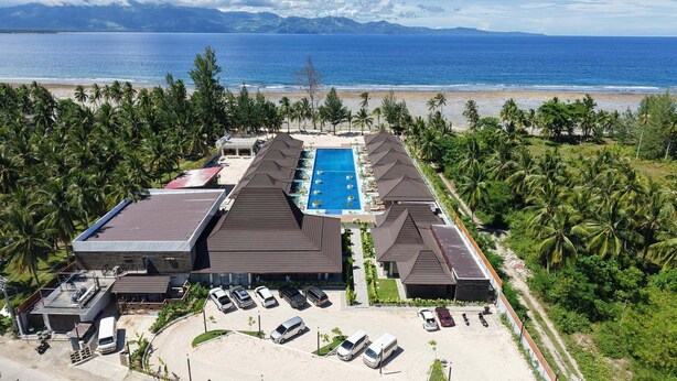 An aerial view of a resort with a swimming pool, beach, and palm trees. - Dahican Beach Resort and Spa (Mati)