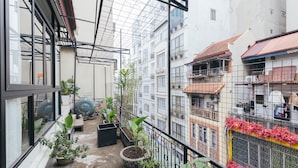 A balcony with potted plants, a metal railing, and a view of adjacent buildings. - Lily Hidden Homestay – Boutique Stay in the Heart of Hanoi Old Quarter (Hà Nội)