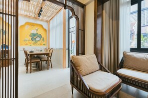 Ein Essbereich mit einem Holztisch und Stühlen, einer gepolsterten Couch und einer Wand mit einem Lotus-Gemälde.