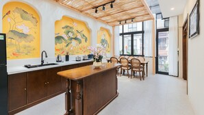 A kitchen with a wooden island, a sink, and a dining area with chairs. - Lily Hidden Homestay – Boutique Stay in the Heart of Hanoi Old Quarter (Hà Nội)