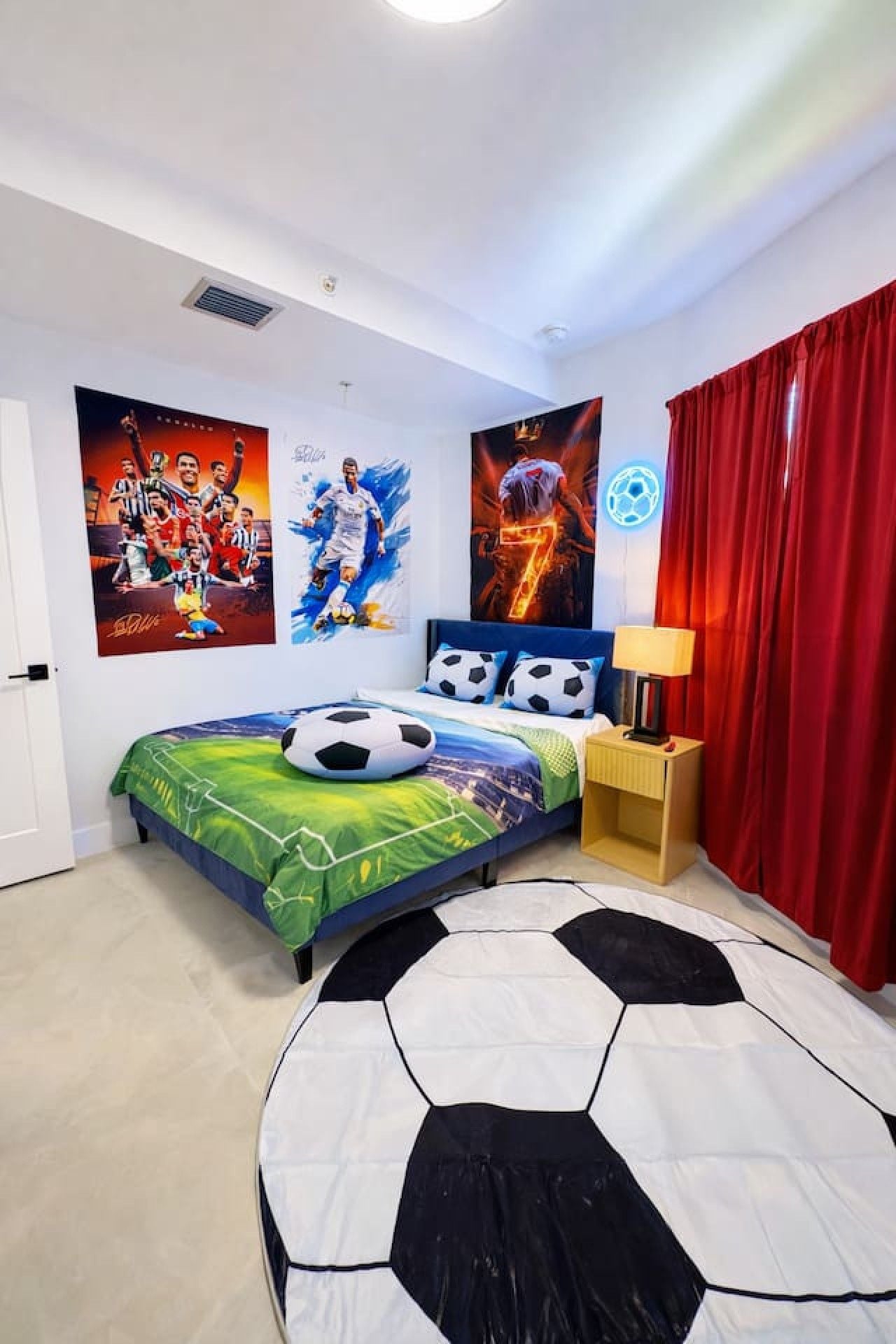 A bedroom with a bed, posters, a lamp, and curtains.