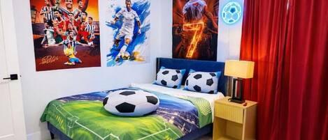 Un dormitorio con cama, carteles, lámpara y cortinas.