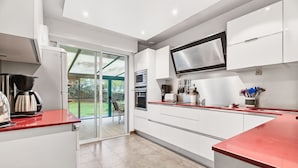 Une cuisine moderne avec des meubles blancs, un plan de travail rouge et une grande fenêtre offrant une vue sur l’extérieur.