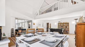 Une salle à manger spacieuse avec un plafond haut et un escalier menant à un niveau supérieur.