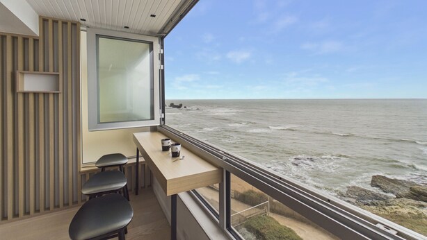 A modern balcony with a view of the sea, a wooden table, and two chairs. - Breathtaking ocean view, stay for 2 (Saint-Hilaire-de-Riez)