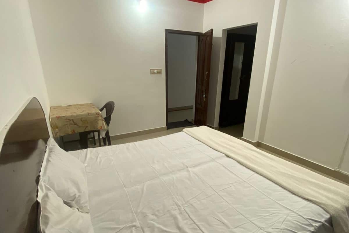 A bedroom with a large bed, a small table, and two doors.