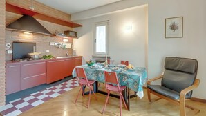 Une cuisine de taille réduite avec un îlot central, une table à manger avec des chaises et un seul fauteuil.