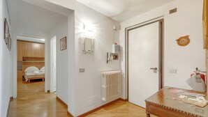 Un couloir avec un plancher en bois, un lit à l’arrière-plan, un radiateur et une table recouverte de papiers.
