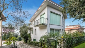 Un immeuble résidentiel de deux étages doté d’un balcon, d’un mur en pierre et d’un chemin pavé.