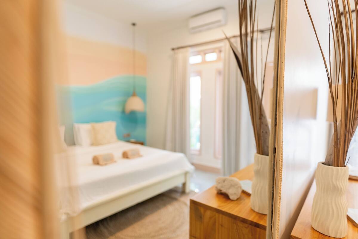 A bedroom with a bed, bedside table, and a mirror.