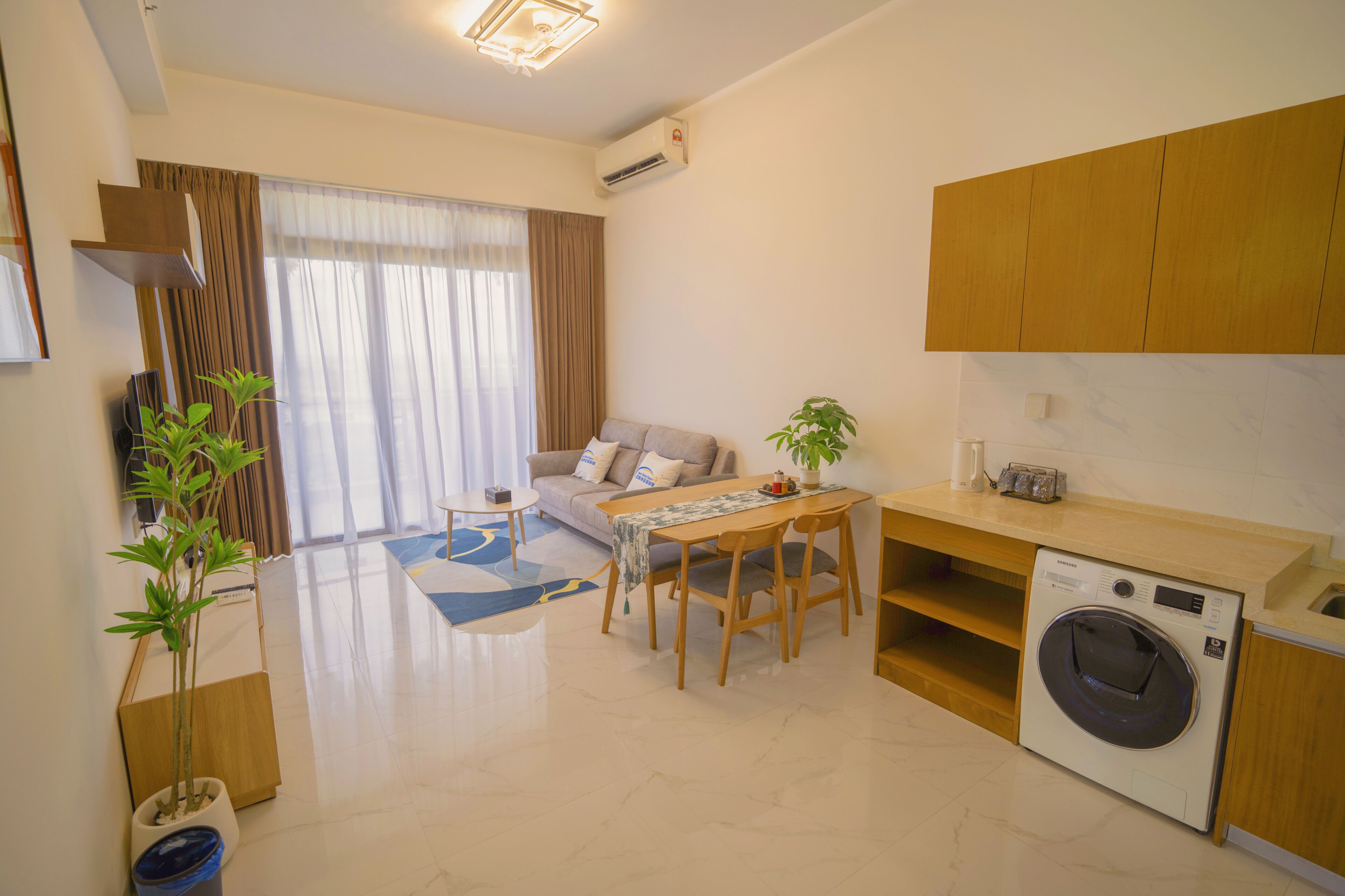 Un appartement moderne comprenant un espace de vie, un coin repas et une cuisine compacte équipée d’un lave-linge.