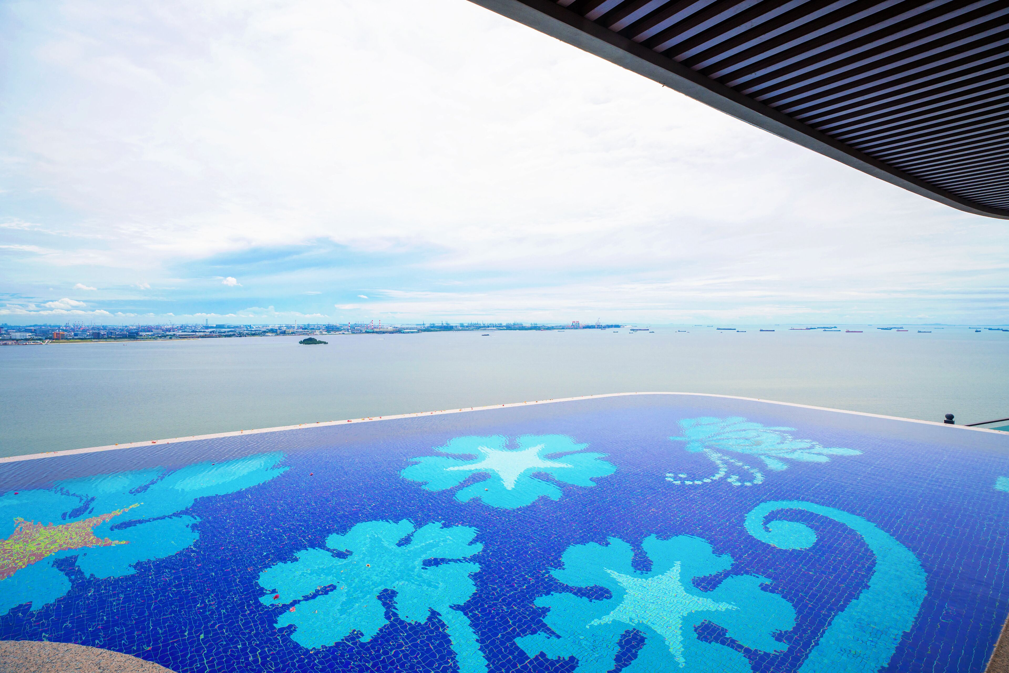 Une vue prise depuis un espace abrité, avec un sol à motifs, une étendue d’eau et une côte lointaine.