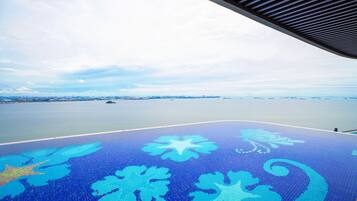 Une vue prise depuis un espace abrité, avec un sol à motifs, une étendue d’eau et une côte lointaine.