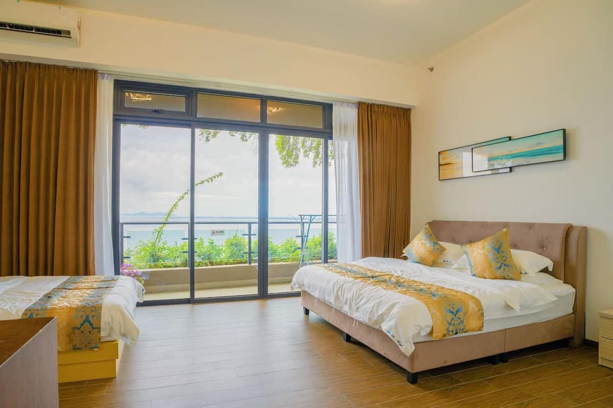 Une chambre d’hôtel avec deux lits, un balcon donnant sur un beau paysage et un tableau accroché au mur.