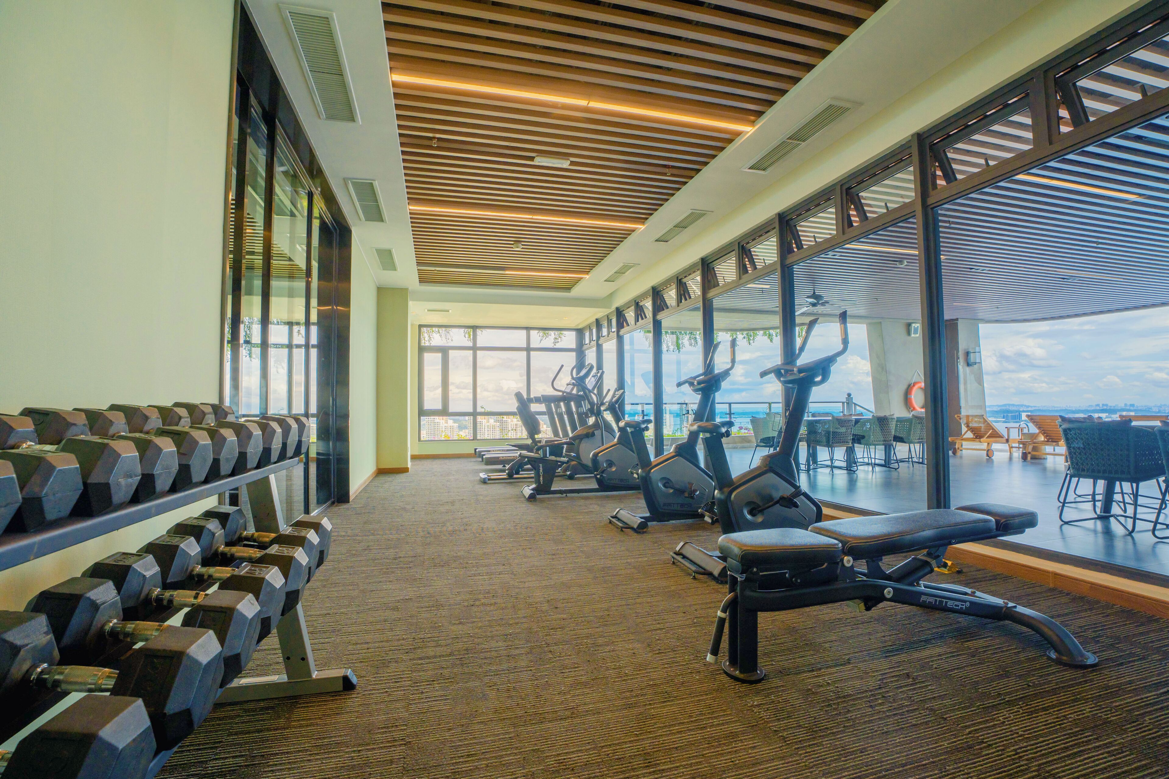 A gym with exercise equipment, a weight rack, and large windows offering a view.