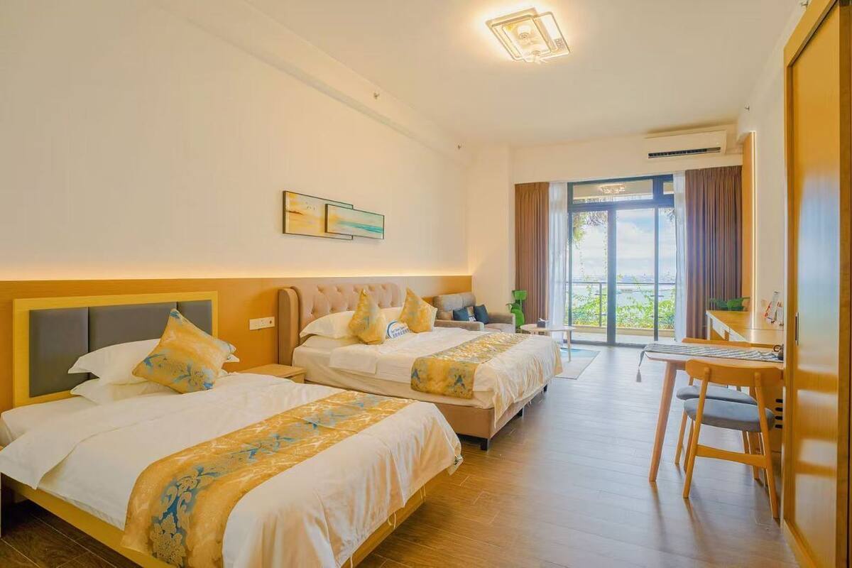 Une chambre d’hôtel avec deux lits, un bureau et une vue sur l’extérieur.