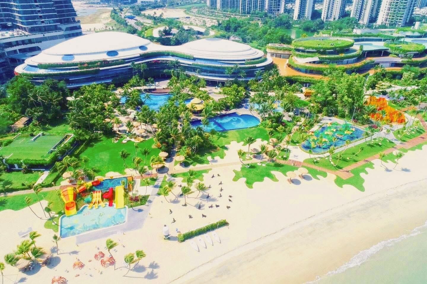 A resort with multiple swimming pools, palm trees, and a beach area.