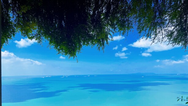 Une vue d’une zone côtière avec des eaux d’un bleu limpide et une ligne de côte lointaine.