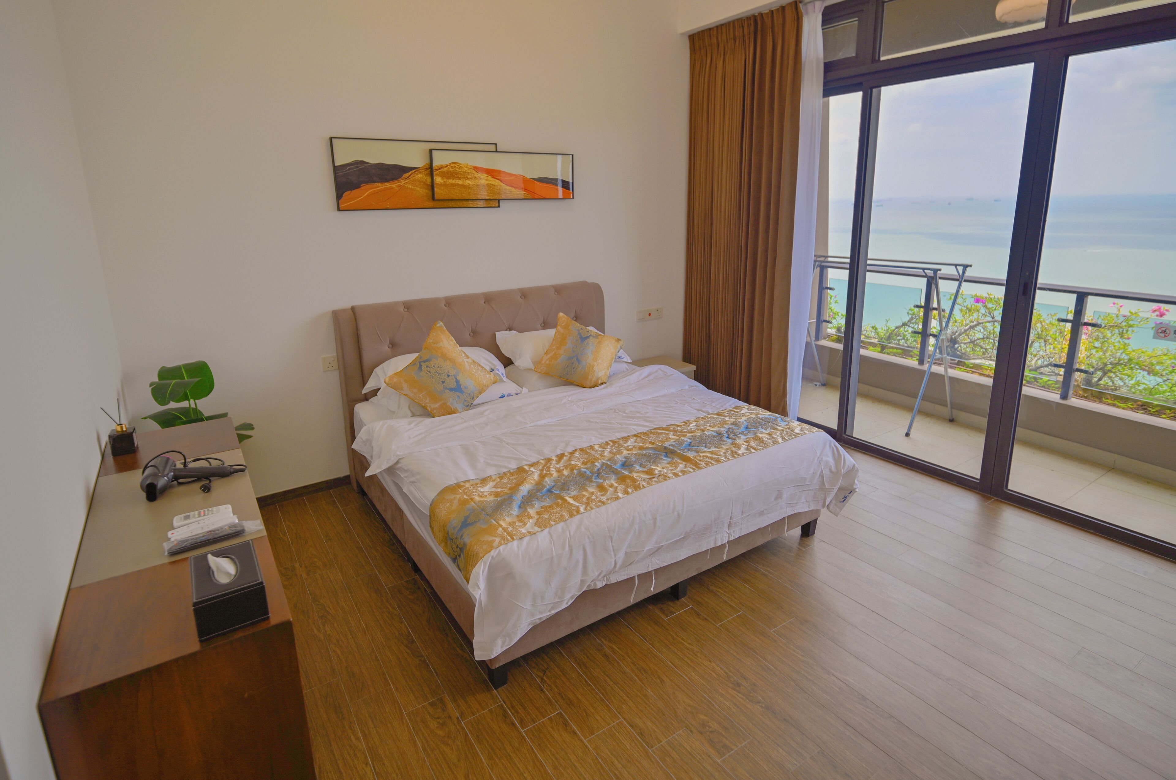 Habitación de hotel con una cama grande, un escritorio con teléfono y vista al mar desde un balcón.