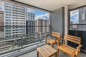 A balcony with two wooden chairs and a small table, overlooking a cityscape with multiple high-rise buildings. - Hilton Grand Vacations Club Tradimo Kyoto Gojo (Kyoto)