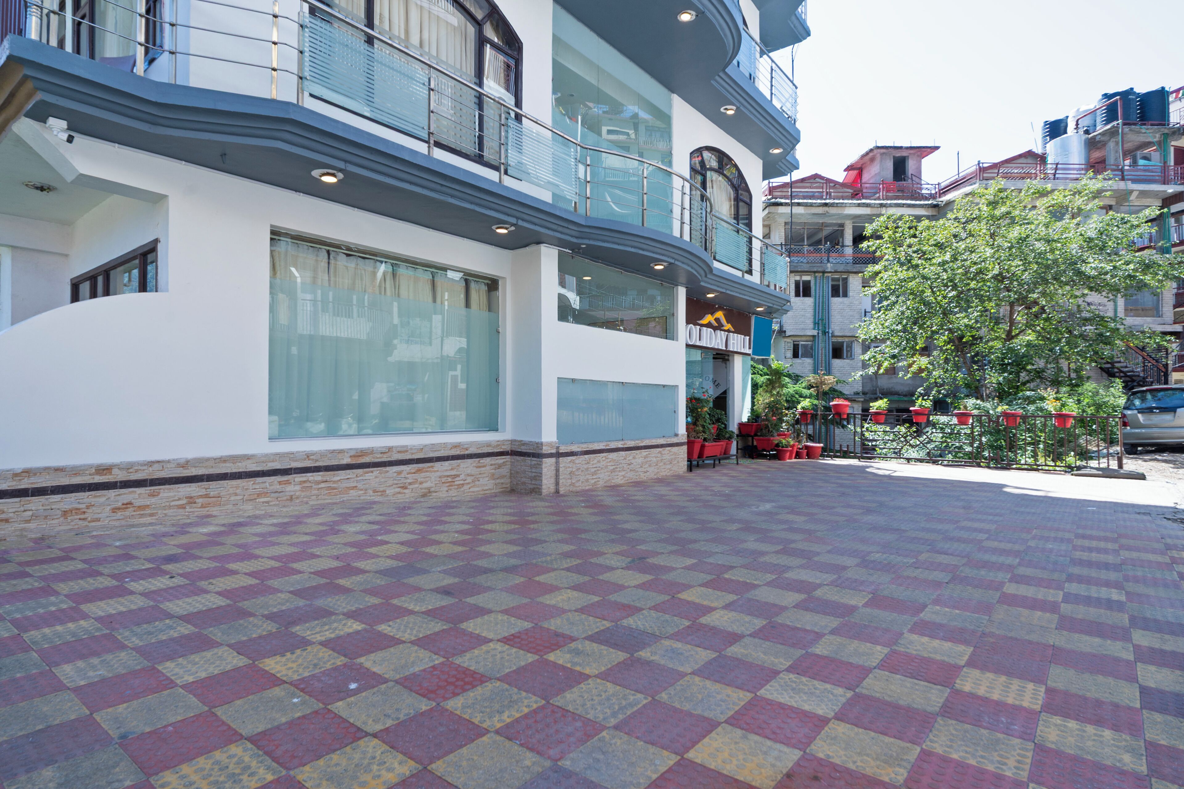 A hotel with a checkered floor, large windows, and a balcony with red chairs.