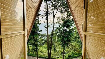 Uma estrutura de madeira triangular com vista para uma paisagem verdejante e exuberante.