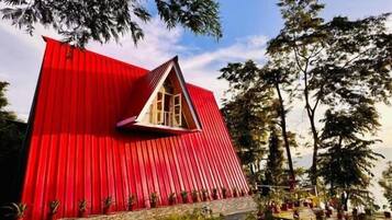 A red, triangular-shaped building with a small window and a stone base.