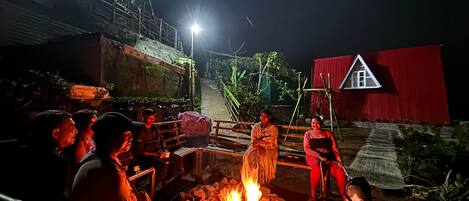 A group of people gathered around a fire pit outdoors at night.