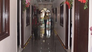 A hallway with a polished floor, wooden doors, and floral decorations. - Shri Awadh Hotel (Sitamarhi)