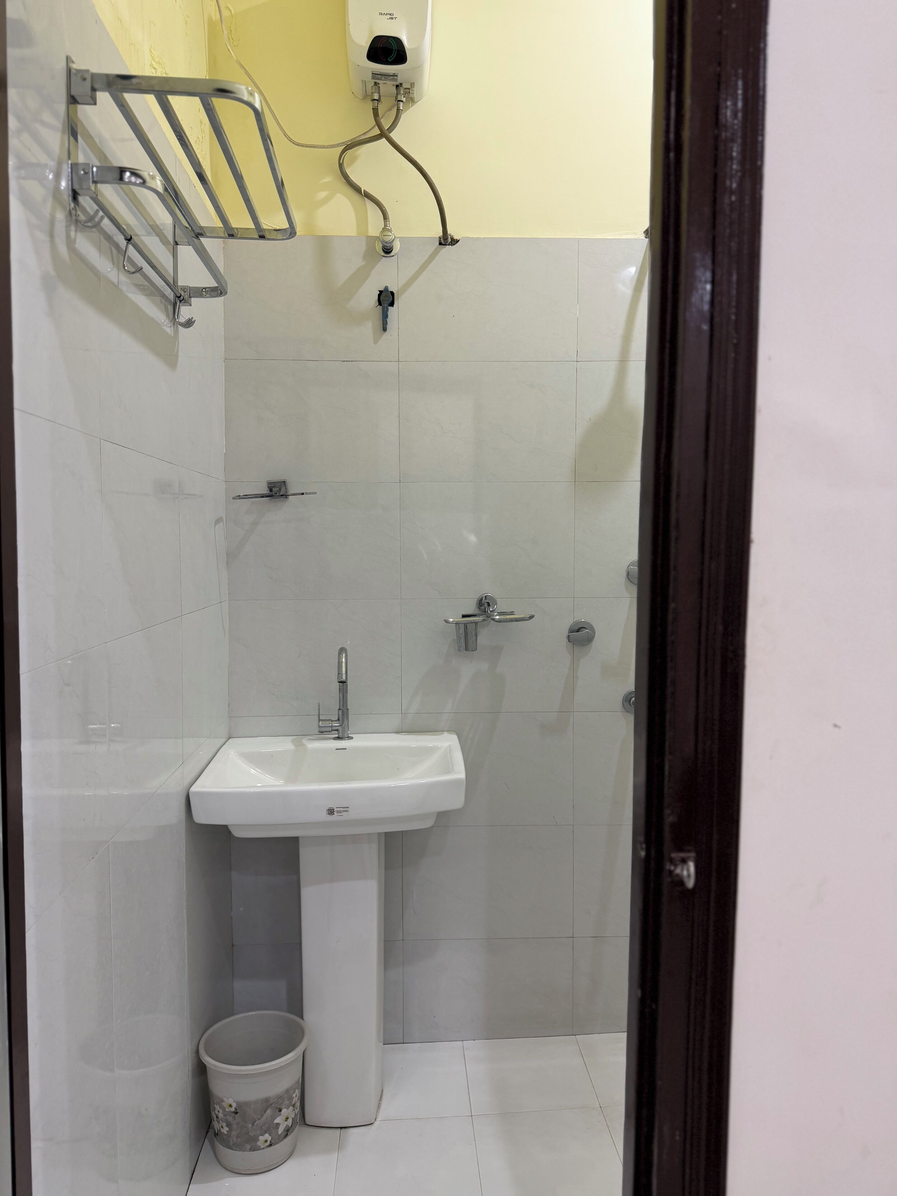 A bathroom with a white sink, a toilet, a trash bin, and a shower area.