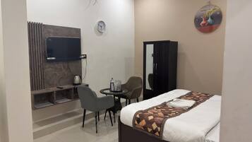 Habitación de hotel con cama, escritorio con silla, televisión, armario y reloj de pared.
