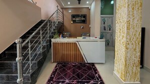 A reception area with a staircase, a reception desk, and a sign welcoming guests to the hotel. - Shri Awadh Hotel (Sitamarhi)