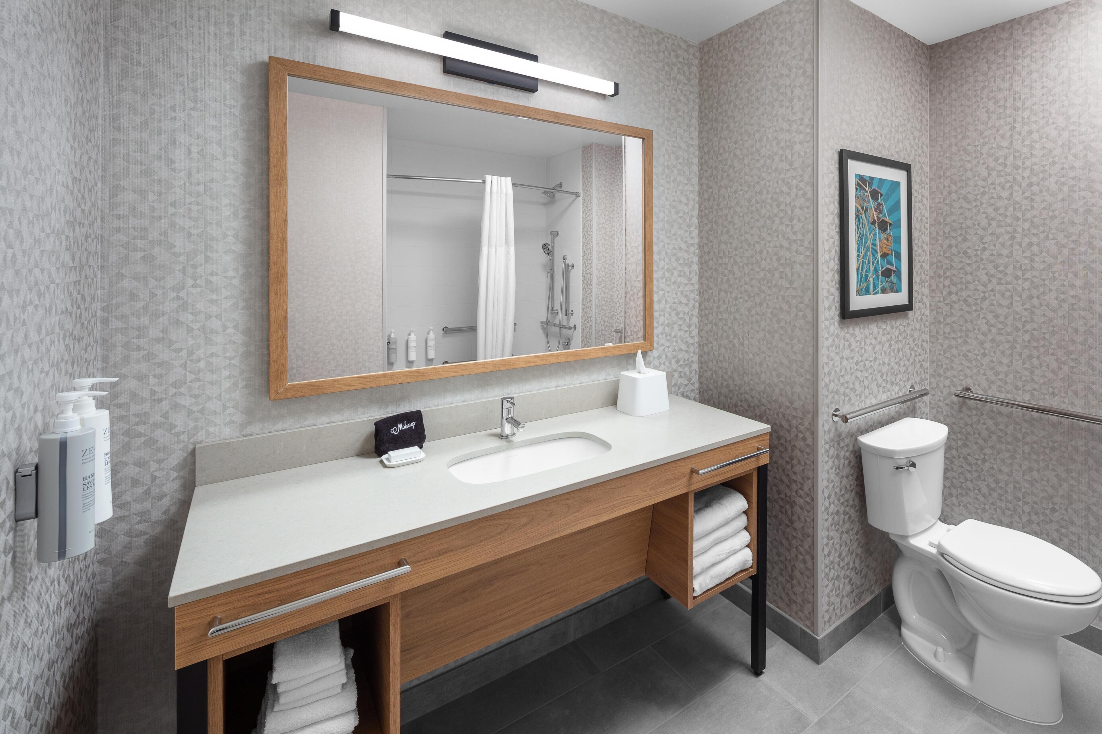 A modern bathroom with a wooden vanity, white sink, and a toilet.