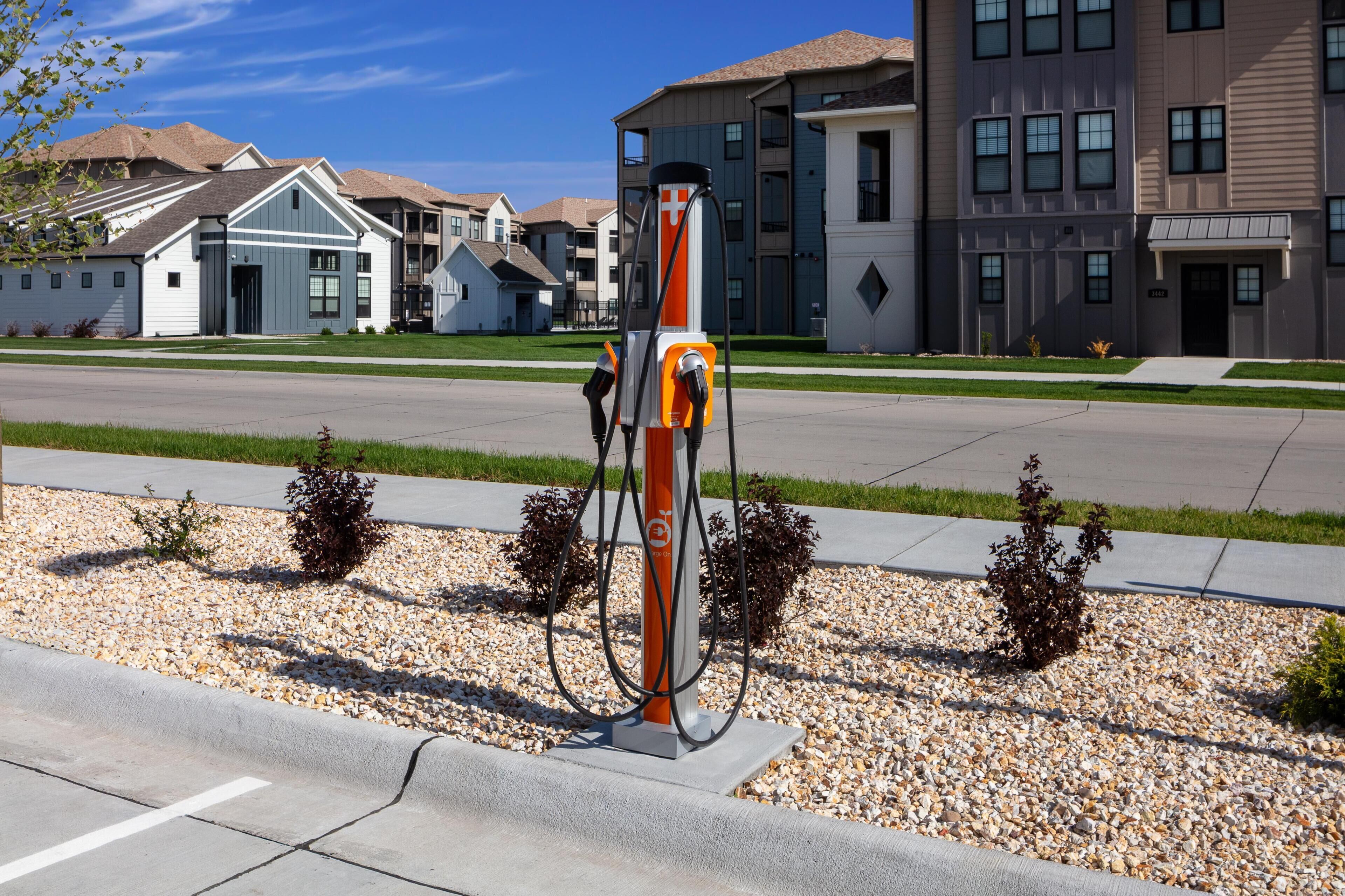 A gas station with a pump, surrounded by residential buildings and a clear sky.
