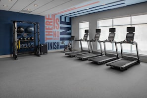 Een fitnessruimte met loopbanden, een krachttrainingrek en een motiverende muur.