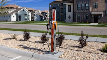 A gas station with a pump, surrounded by residential buildings and a clear sky.