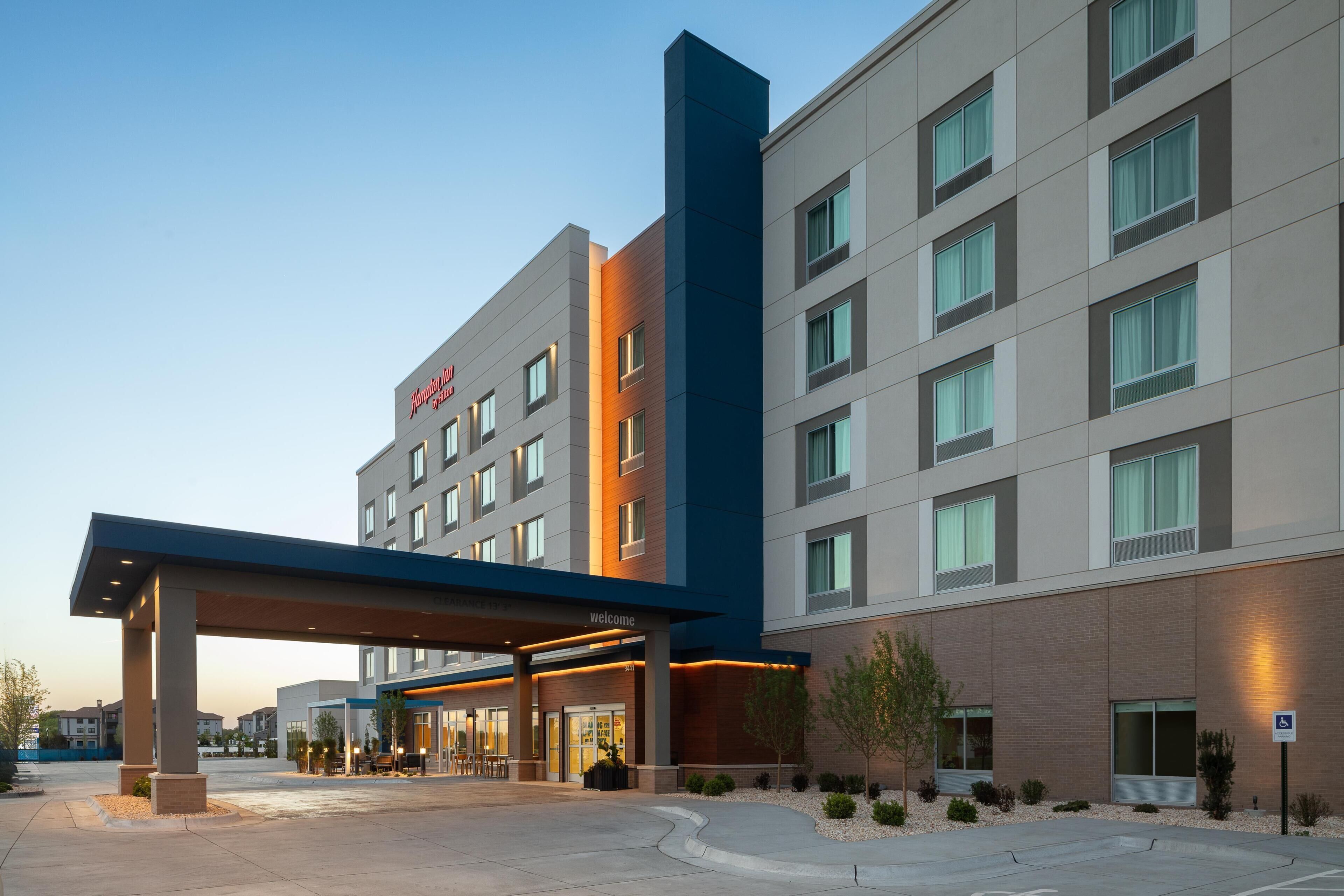 Un hotel moderno con un llamativo letrero de 'Marriott', una entrada cubierta y un área de estacionamiento.