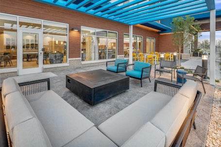 An outdoor patio with a fire pit, seating area, and large windows.. Hampton Inn by Hilton Grand Island Medical Center