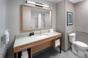 A modern bathroom with a wooden vanity, white sink, and a toilet.