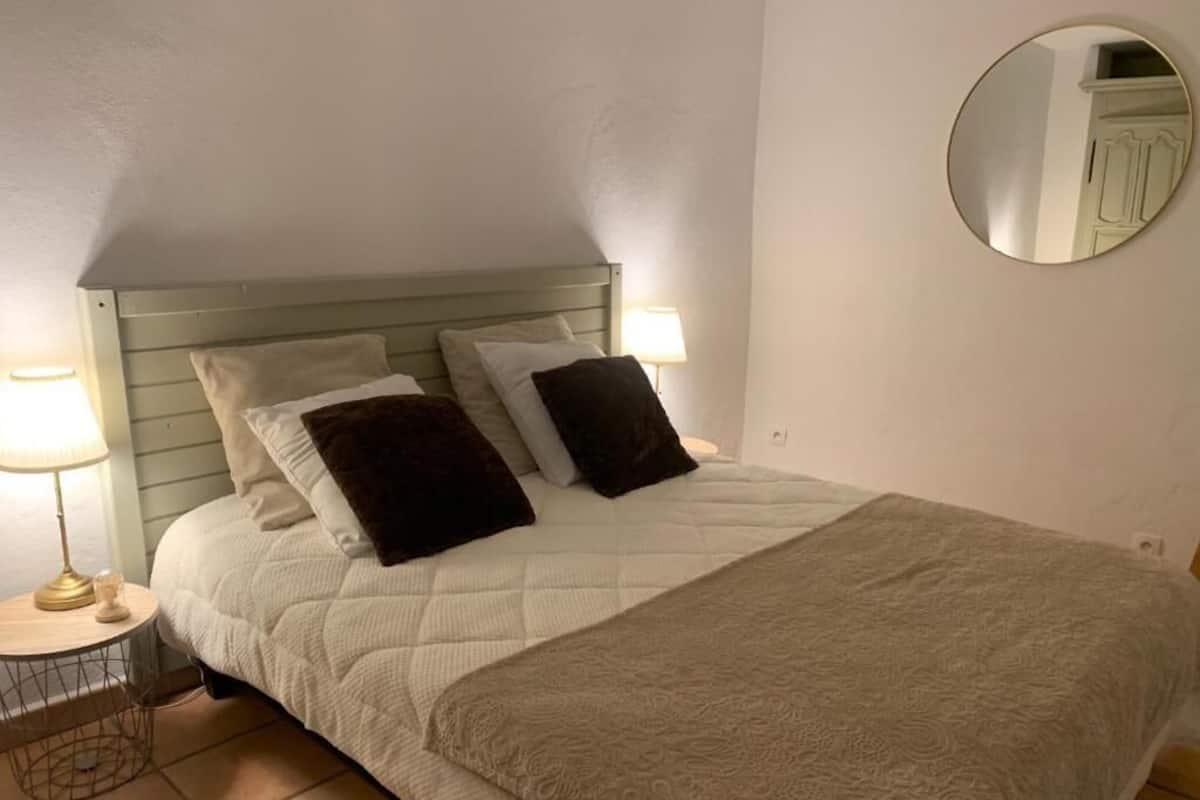 Ein Bett mit Kopfteil, zwei Nachttischlampen und einem runden Spiegel an der Wand.