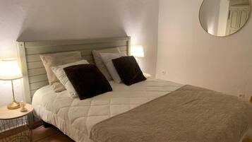A bed with a headboard, two bedside lamps, and a round mirror on the wall.