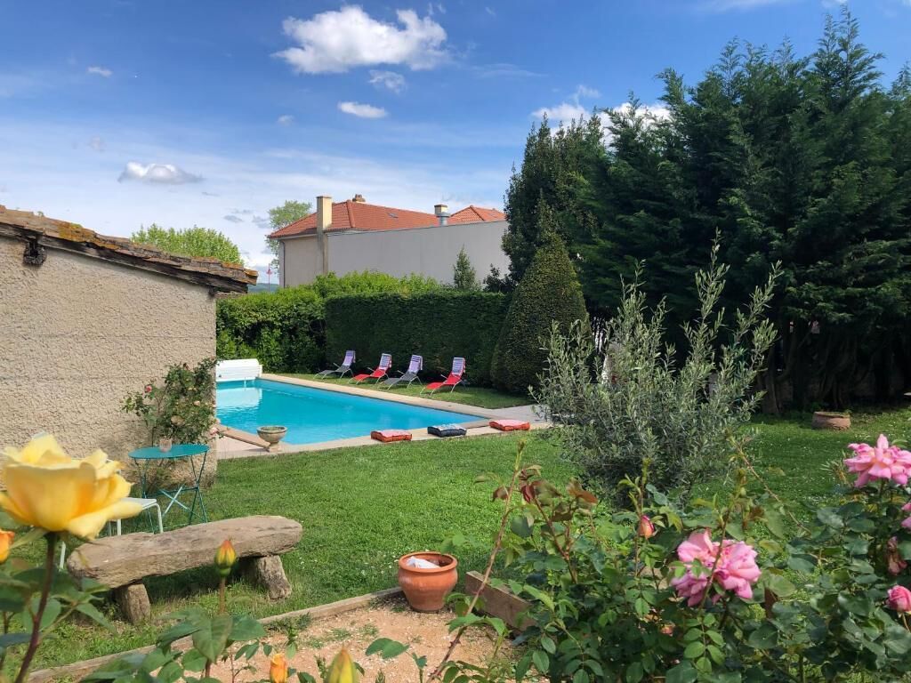 A backyard with a swimming pool, lounge chairs, and a garden with flowers.