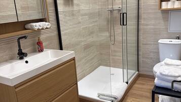 A modern bathroom with a glass shower enclosure, a wooden vanity with a sink, and a toilet.