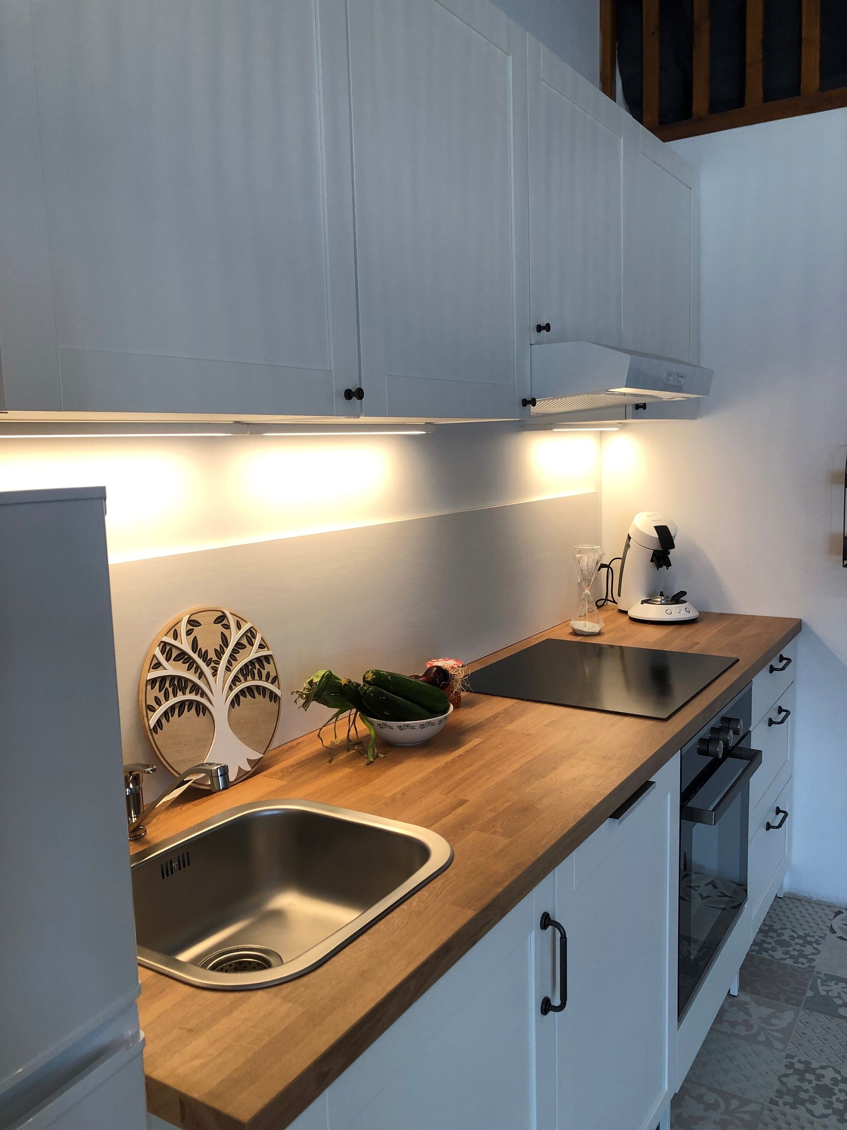 Une cuisine moderne avec des plans de travail en bois, un évier en acier inoxydable et des armoires blanches.
