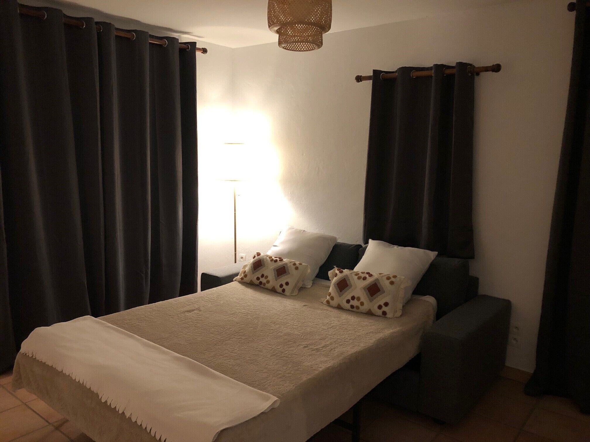 Une chambre à coucher avec un lit, deux oreillers, une table de chevet et une lampe.